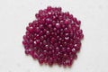 Ruby stones lie on a white table, a white background. Natural stones ruby, ruby beads. Pink ruby background