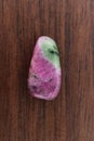 Ruby zoisite stone texture on brown varnished wood background. Macro closeup Royalty Free Stock Photo