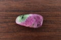 Ruby zoisite stone texture on brown varnished wood background. Macro closeup Royalty Free Stock Photo