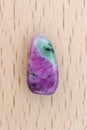 Ruby zoisite stone texture on light varnished wood background. Macro closeup Royalty Free Stock Photo
