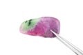 Ruby zoisite stone texture in tweezers on light surface background. Macro closeup Royalty Free Stock Photo