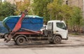 ÃÂ¢ruck with full blue container for construction debris on board is standing outside.