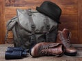 Rucksack with old boots, binoculars and hat on wooden background