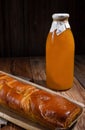 Ruddy pie with orange filling, bottle of pumpkin juice, wooden table, rustic style
