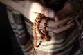 Rudraksha beads in men`s hands in traditional indian shawl. Man counting religious beads in sunlight.