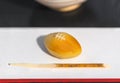 Rugby ball shaped Japanese confection called wagashi or namagashi and a kuromoji skewer. Royalty Free Stock Photo