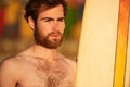 Rugged bearded male surfer portrait next to surf board