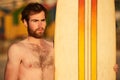 Rugged bearded male surfer portrait next to surf board