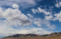 Rugged dessert hills in the distance under a huge fantastically blue sky with beautiful fluffy white clouds Royalty Free Stock Photo