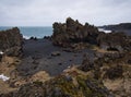 Rugged lava rocks on a black sandy beach Royalty Free Stock Photo