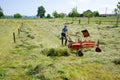 Rugged male farmer harvesting hay with a small tractor