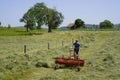 Rugged male farmer harvesting hay with a small tractor