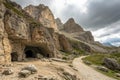 Rugged mountain landscape with cave entrance and path under cloudy sky in daylight Royalty Free Stock Photo