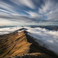 Rugged mountain ridges rise above thick, rolling clouds, casting a dramatic scene. A Royalty Free Stock Photo