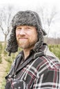 Rugged outdoorsman in fur hat and ear flaps, outside in winter,