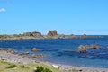 Rugged rocks jut out into the calm sea at a deserted beach on the Cook Strait near Wellington, New Zealand Royalty Free Stock Photo