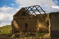 Ruin of a farm house on a green field with sheep grazing.