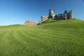 Ruin of medieval fortress sitting on grassy hill Royalty Free Stock Photo