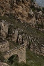 Ruin of medieval stone fort on rocks with arch in highlands of Dagestan in summer, detail of abandoned and destruction building. Royalty Free Stock Photo