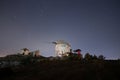 Ruin windmill in the night sky. A view of the stars of the Milky Way with a mountain top in the foreground.