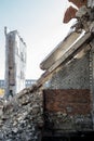 A ruined brick wall with hanging pieces of supports on the background of the remains of a destroyed building. Background