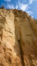 Ruined clay slope on the coast. Cracked clay cliff on the coast. A crumbling and cracked clay wall.