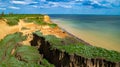 Ruined clay slope by the sea. Cracked clay cliff on the coast.