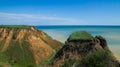 Ruined clay slope by the sea. Cracked clay cliff on the coast.