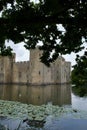 A ruined English medieval castle Bodiam Castle, UK reflected in a moat, seen through trees Royalty Free Stock Photo