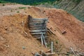 A ruined large log mine high in the mountains. Extraction of minerals in the highlands. The rock is red and orange.