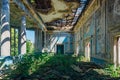 Ruined mansion hall interior overgrown by plants. Nature and abandoned architecture, green post-apocalyptic concept