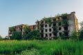Ruined overgrown apartment house with bullet marks in ghost town, consequences of war in Abkhazia, green post-apocalyptic concept