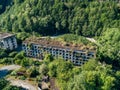 Ruined overgrown apartment house in ghost mining town, consequences of war in Abkhazia, aerial view from drone