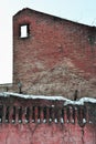 Ruined red brick wall with window hole, snow covered fence wall Royalty Free Stock Photo