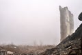 The ruined remains of a building with a pile of concrete rubble and bricks against the background of a building wall in a hazy Royalty Free Stock Photo