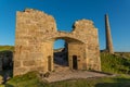 The old arched wall of Brunton calciner, with tin mine chimney, at Botallack, Cornwall Royalty Free Stock Photo