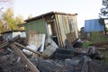 Ruined wooden house. Around different trash, tires, boards