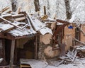 Ruined wooden house on the background of snowy trees and new buildings. A winter. Royalty Free Stock Photo