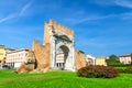 Ruins of ancient brick wall and stone gate Arch of Augustus Arco di Augusto, green lawn with bush of flowers in Rimini Royalty Free Stock Photo