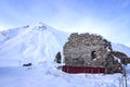 The ruins of an ancient building on the background of a snowy mountain at Cross Pass Georgian Military Highway