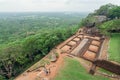 Ruins of ancient city palace on Sigiriya rock and some tourists walking around archeological area Royalty Free Stock Photo