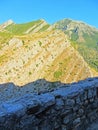 The ruins of an ancient fortress. old thick stone walls of a European fortress overgrown with greenery in the mountains. Doors and Royalty Free Stock Photo