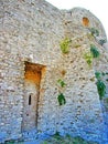 The ruins of an ancient fortress. old thick stone walls of a European fortress overgrown with greenery in the mountains. Doors and Royalty Free Stock Photo