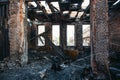 Ruins of burned brick house after fire disaster accident. Heaps of ash and arson, burnt furniture, collapsed roof, broken windows