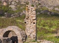 Ruins of the castle, elements of the buildings arch column stone on the background of the high mountains below grows the green