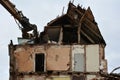 The ruins of an earthquake-damaged residential building with broken walls, brick fragments and roof are being dismantled by an