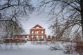 The ruins of the old manor house built of red brick with pillars in the front located in the thickets of bushes, winter snow day. Royalty Free Stock Photo