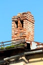 Ruins of old red brick chimney on top of abandoned building with metal roof and rusted edge surrounded with gutter Royalty Free Stock Photo