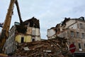 The ruins of an earthquake-damaged residential building with broken walls, brick fragments and roof are being dismantled by an