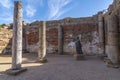 Ruins of a Roman hall with columns and the bronze statue of the actress Margarita Xirgu from the Roman Theater .
